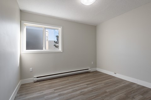 an empty room with wood floors and a window