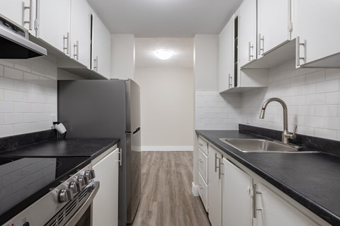 a kitchen with black counter tops and white cabinets and a stainless steel refrigerator