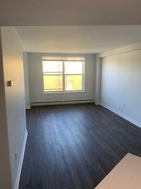 an empty living room with wood floors and a window