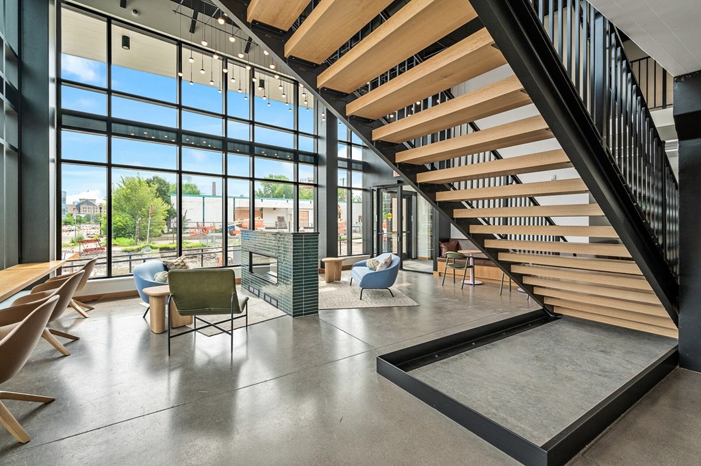the lobby of a building with a staircase and tables and chairs