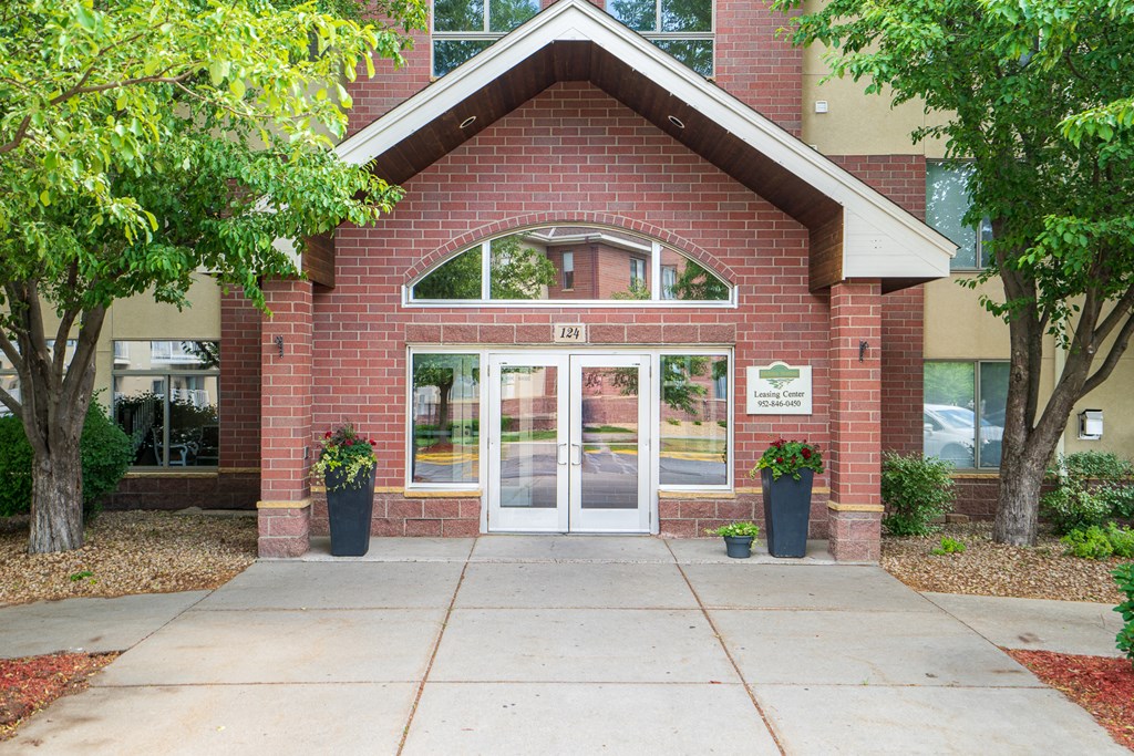 the entrance to a brick building with glass doors and a sidewalk