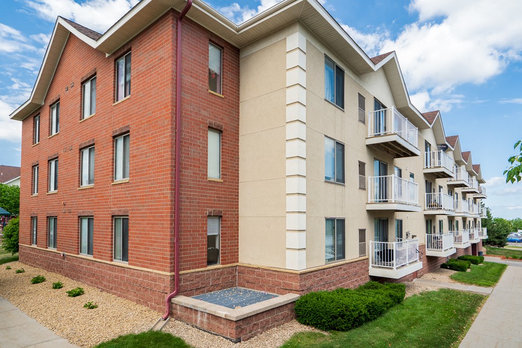 a large brick apartment building with balconies and a sidewalk