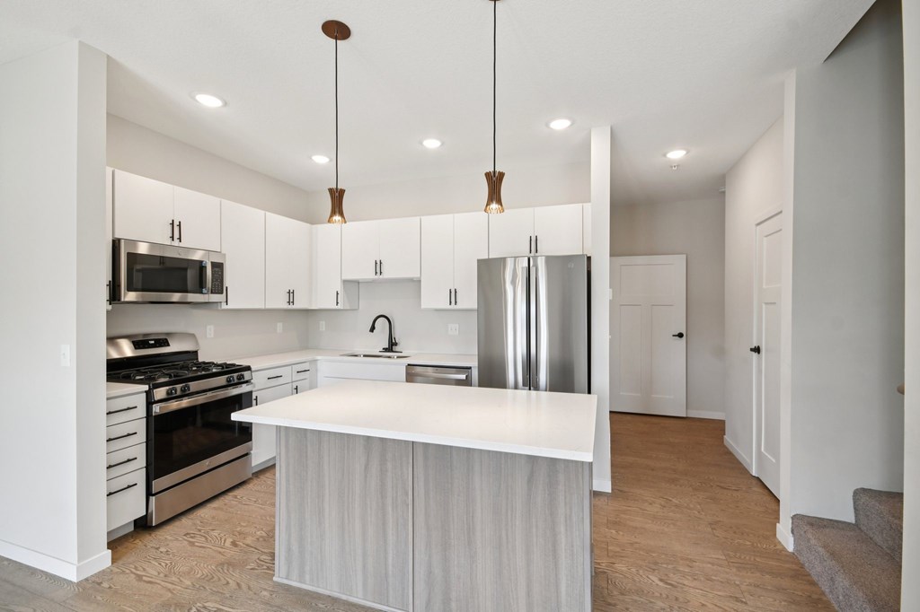 A modern kitchen with white cabinets and a large island at Ironwood Townhomes in Medina, MN.