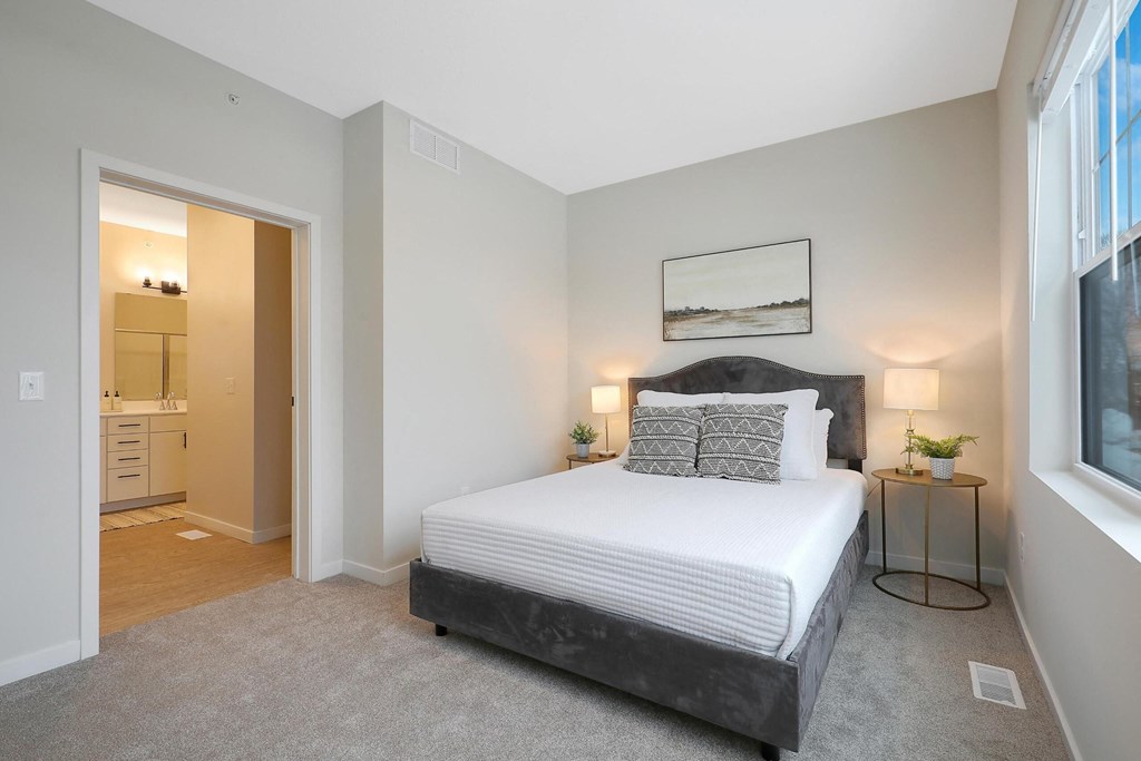 A bedroom with a large bed and a small table with a lamp.