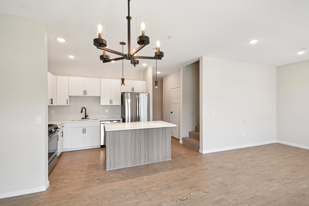 A modern kitchen with a large island and a chandelier at Ironwood Townhomes in Medina, Minnesota.