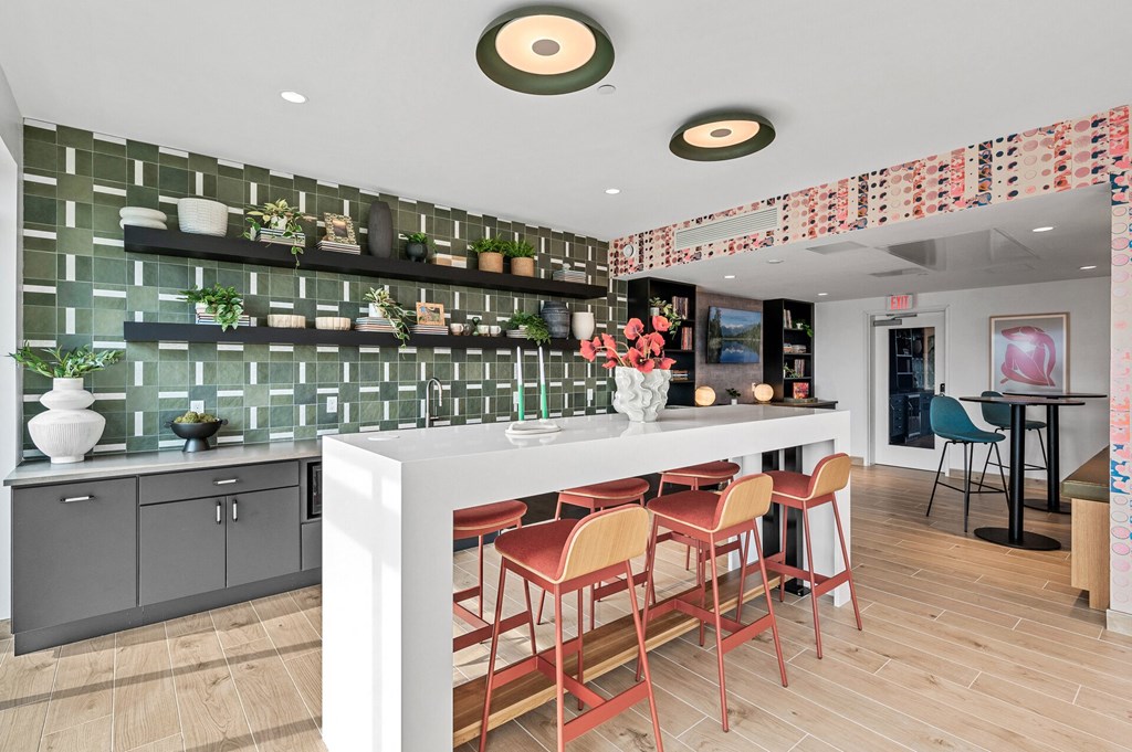 Community room kitchen with a long white counter and a bar with chairs