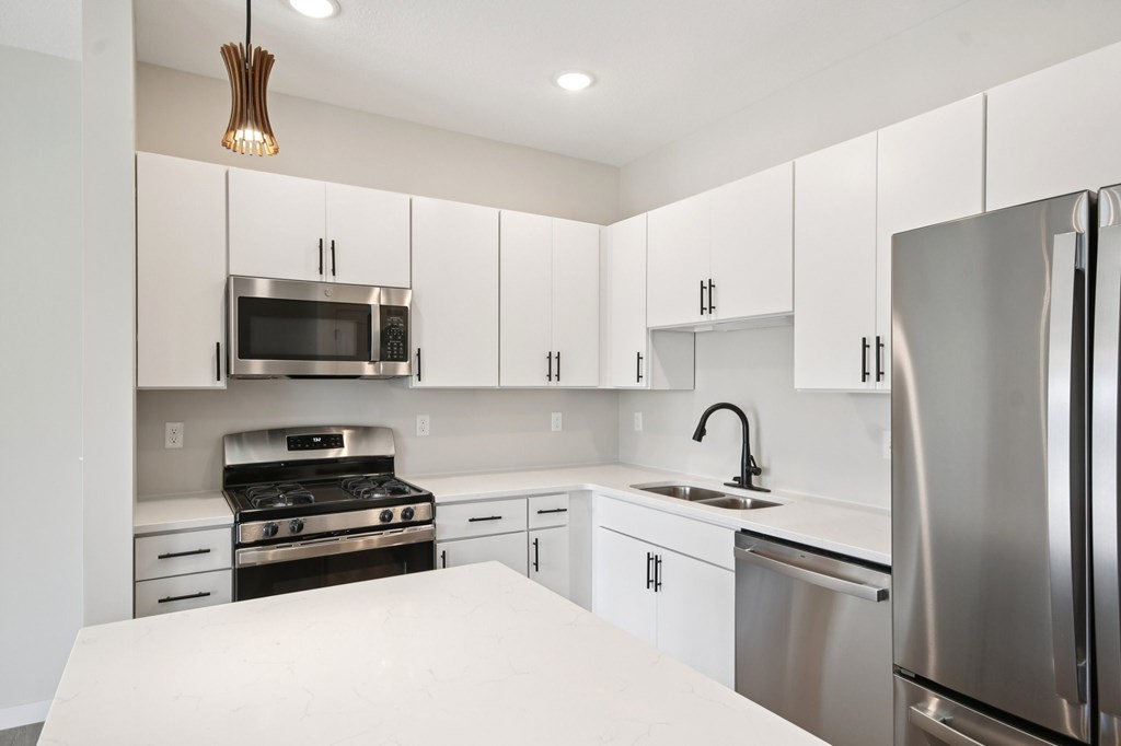 A modern kitchen with white cabinets and stainless steel appliances at Ironwood Townhomes in Medina, Minnesota.