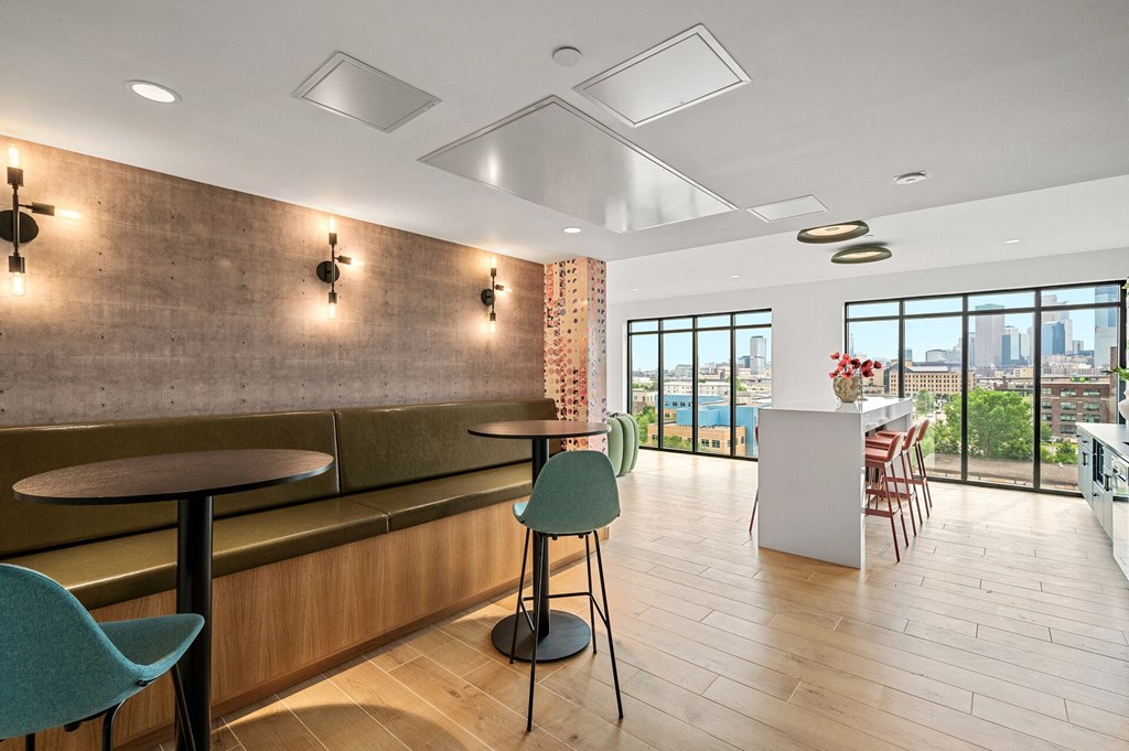 a seating area with tables and chairs and a counter in a room with windows