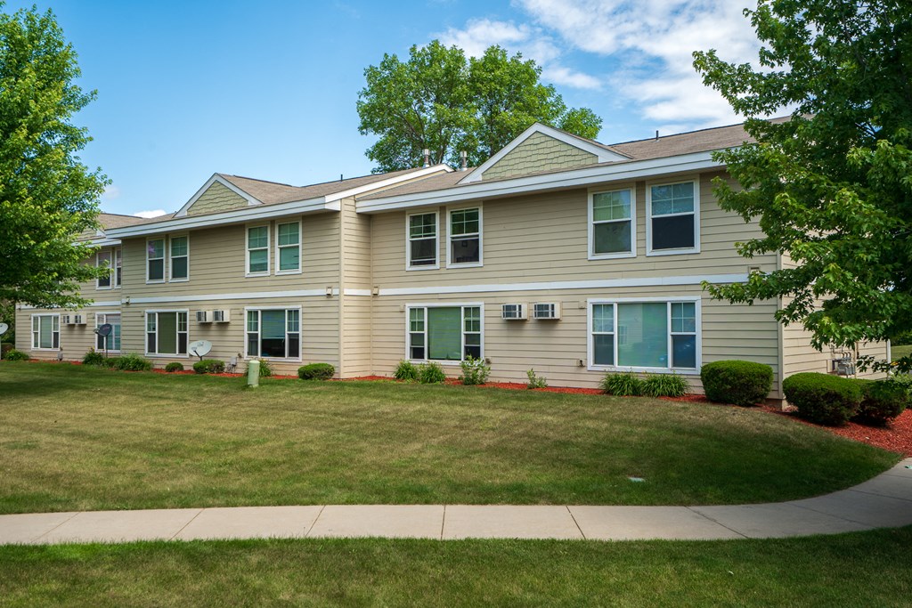 the front of a house with a lawn and trees