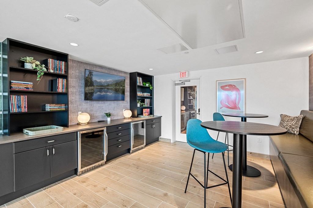 Community room with a table and chairs and a kitchen with black cabinets