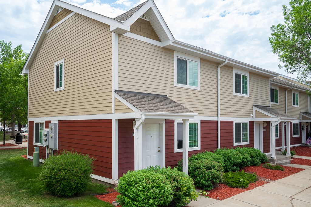 a red and tan house with a sidewalk in front of it