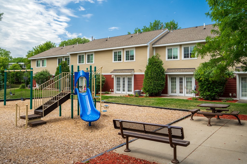 a playground in front of a house with a blue slide