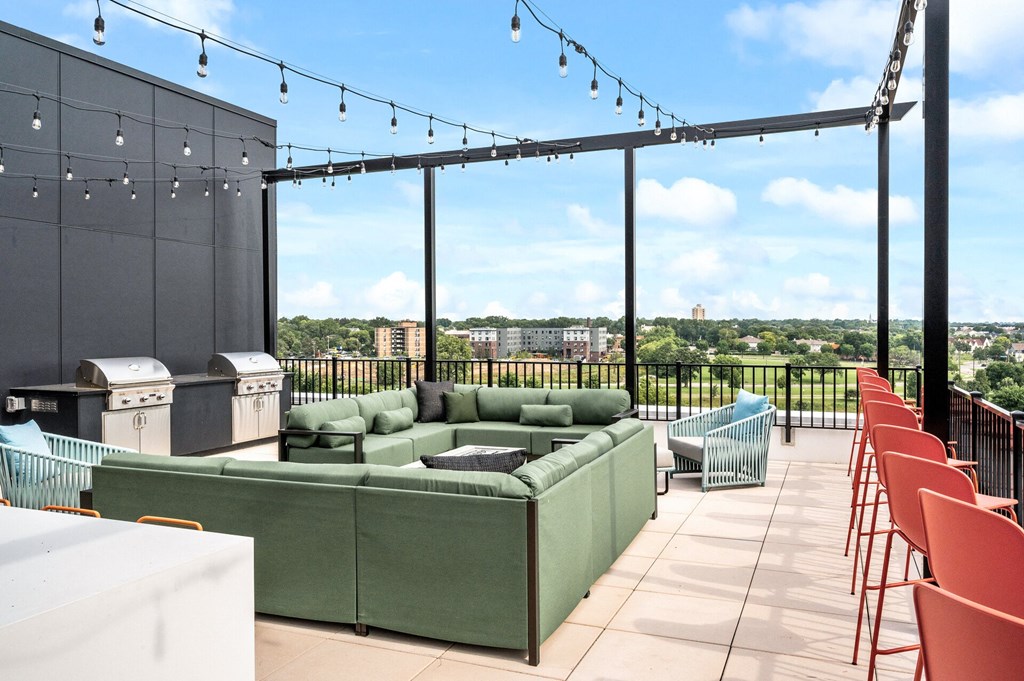 a rooftop patio with green couches and chairs and a bar