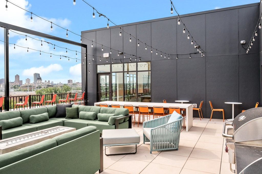 a rooftop patio with green couches and chairs and a table with chairs
