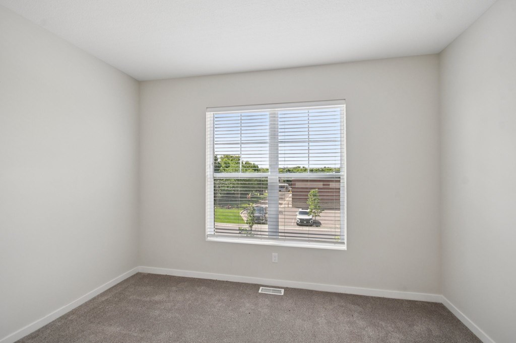 A room with a window showing a view of a fence and a tree.