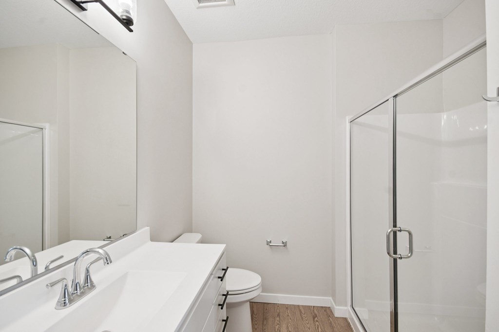 A white bathroom with a sink, toilet, and shower at Ironwood Townhomes in Medina, Minnesota.