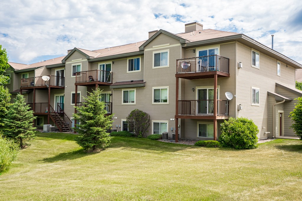 the view of an apartment building with a lawn and trees