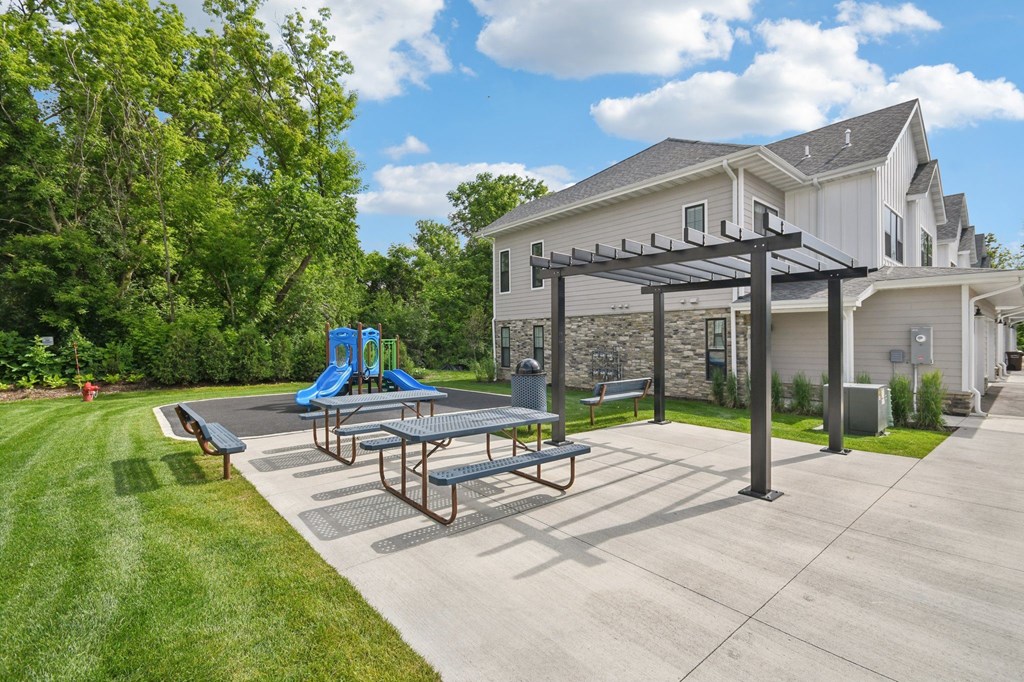 A playground area with a slide and picnic table in front of a house  at Ironwood Townhomes in Medina, Minnesota.