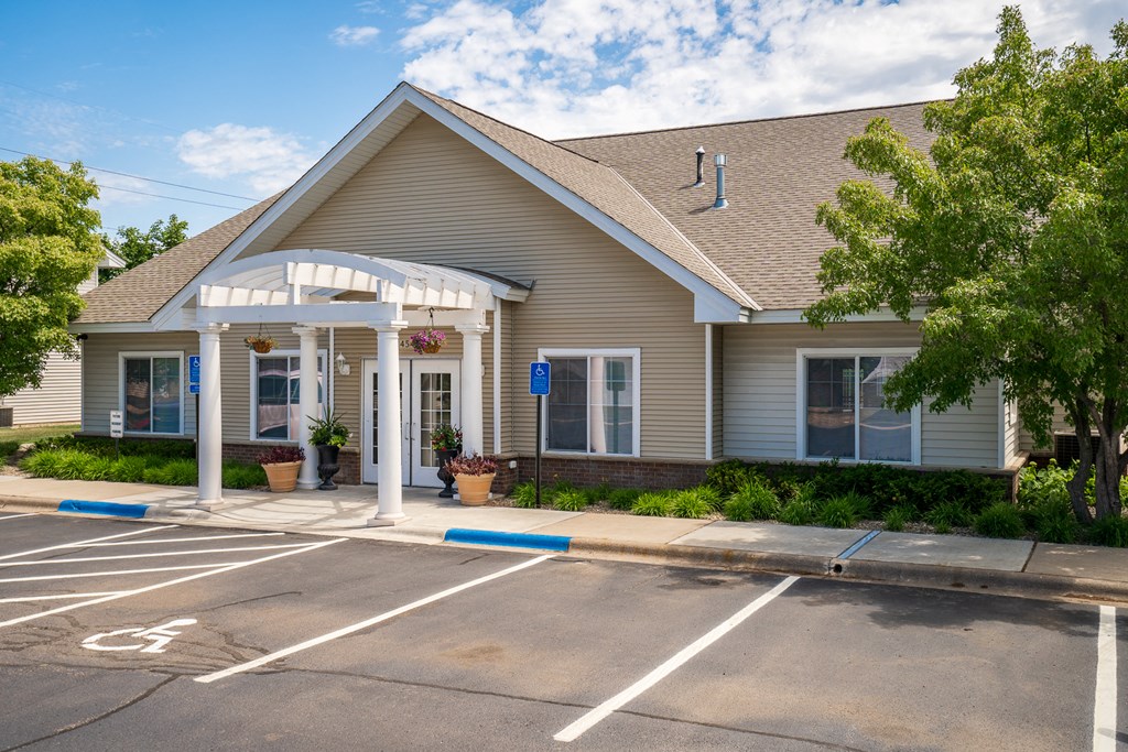 the front of a building with a parking lot and a porch
