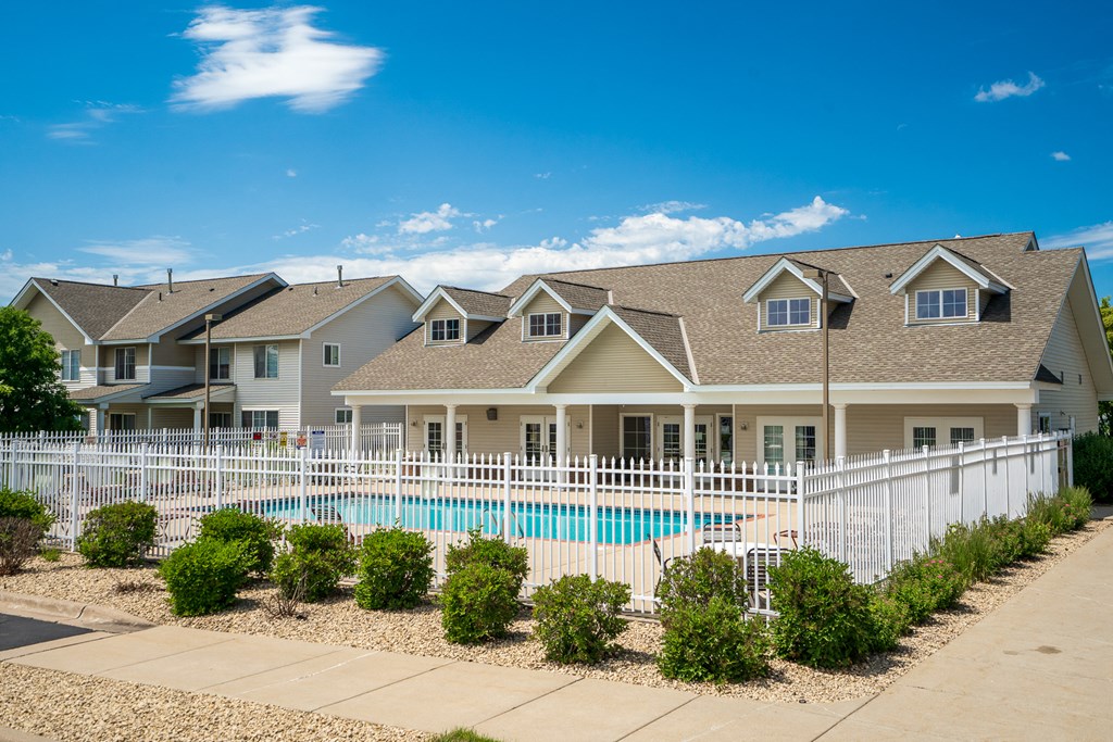 a house with a pool behind a white fence