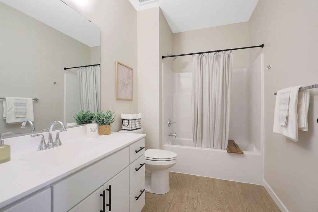 A white bathroom with a toilet, sink, and shower.