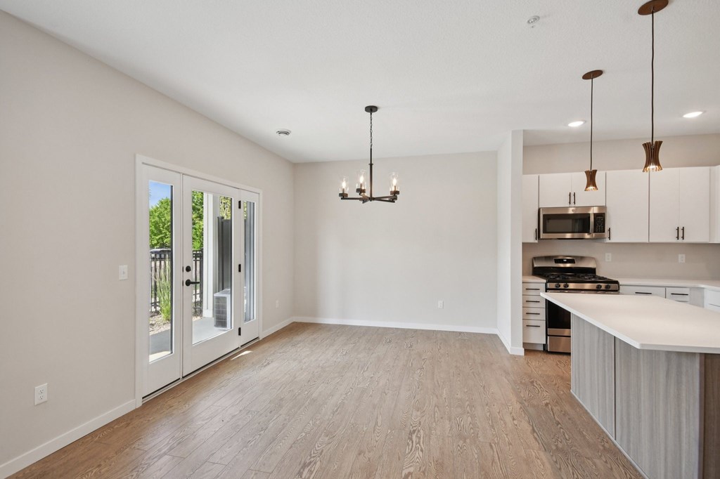 A spacious kitchen and living room with a view of the backyard through the sliding glass doors at Ironwood Townhomes in Medina, Minnesota..