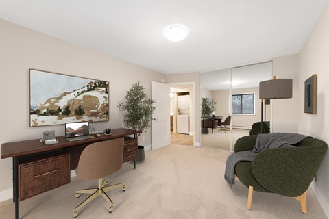 A room with a desk, chair, and a painting on the wall.