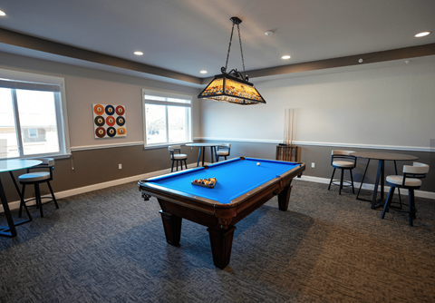A pool table in a room with a hanging light fixture.