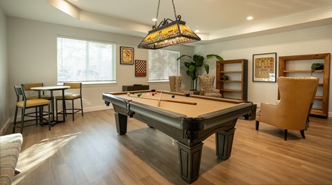 A pool table is in the middle of a room with a light hanging from the ceiling.