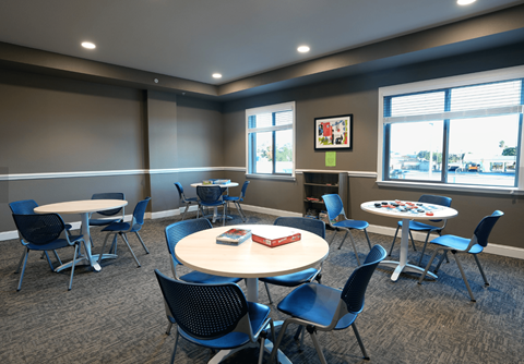 A room with tables and chairs and a window.