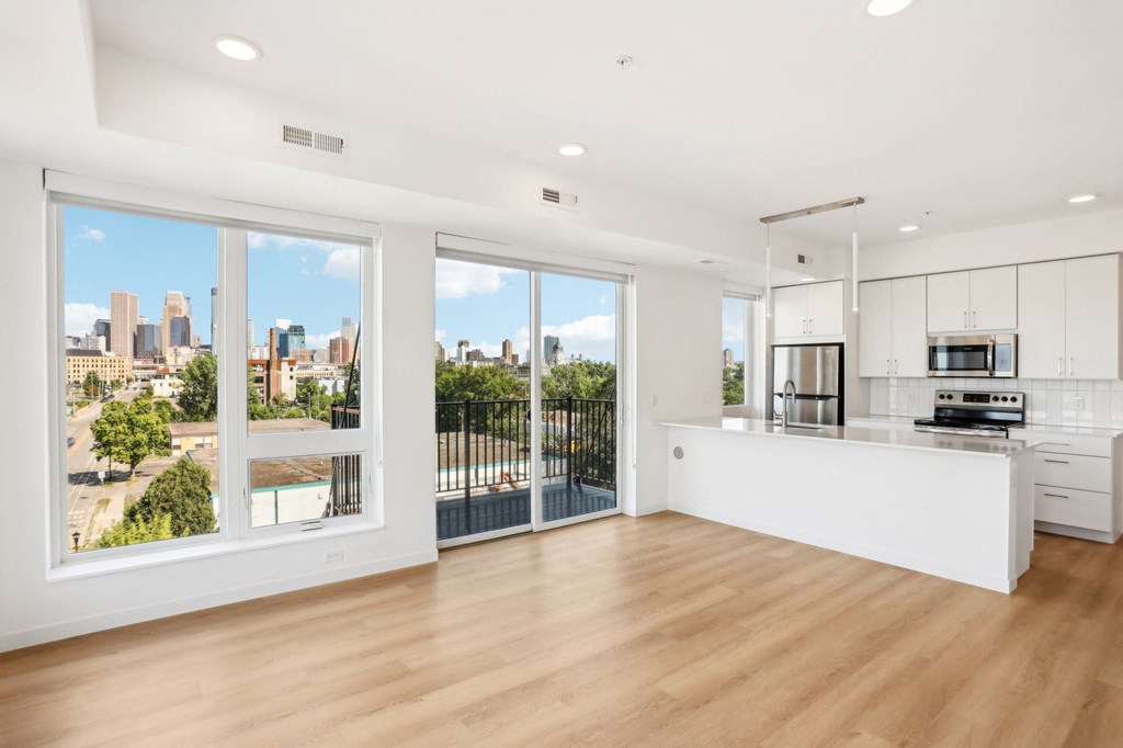 an open living room with a kitchen and a balcony overlooking a city