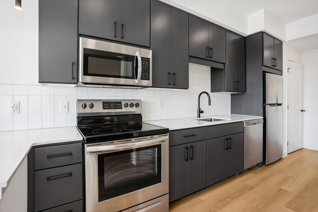 a black and white kitchen with stainless steel appliances and black cabinets