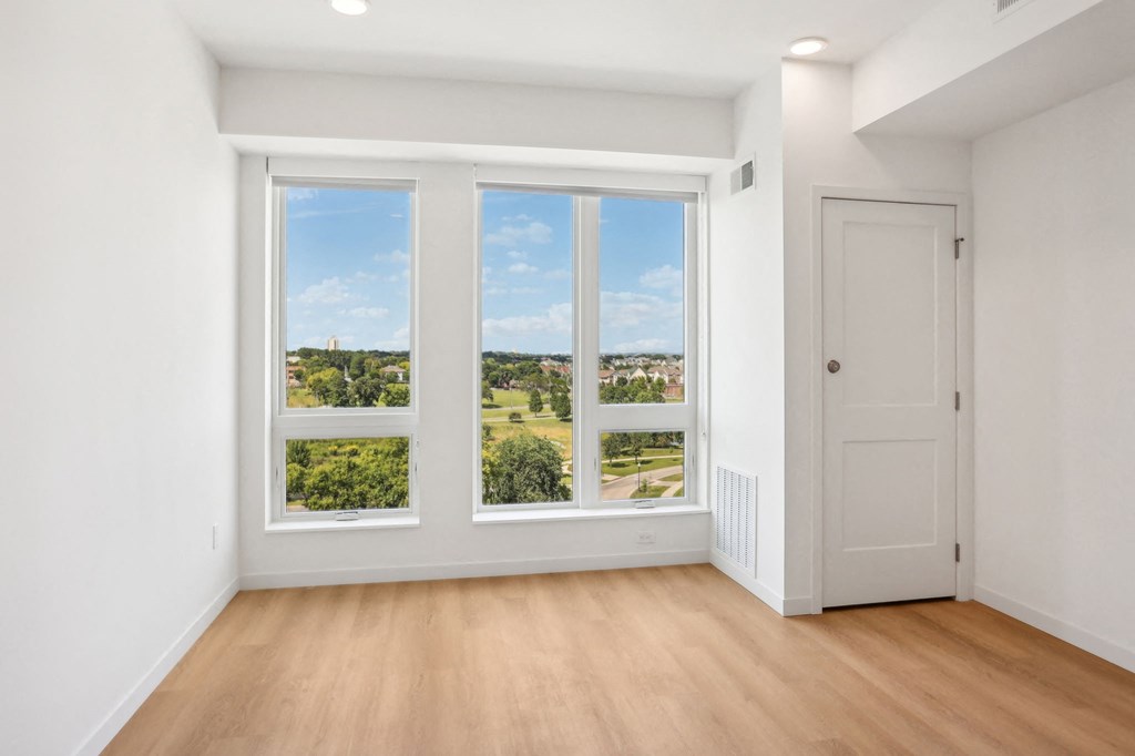 an empty living room with large windows and a door
