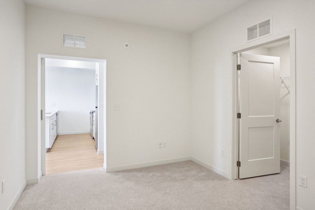 a bedroom with white walls and a door to a hallway