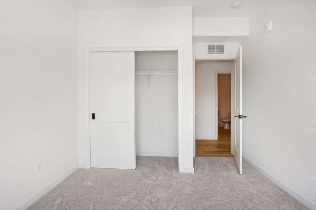 a bedroom with white walls and a closet with white doors