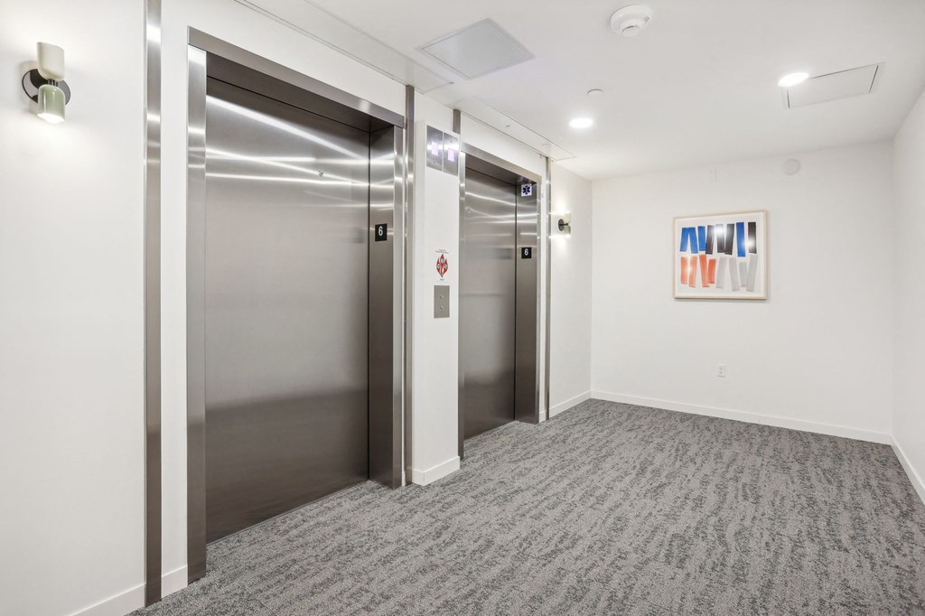 an empty room with two elevators and a painting on the wall