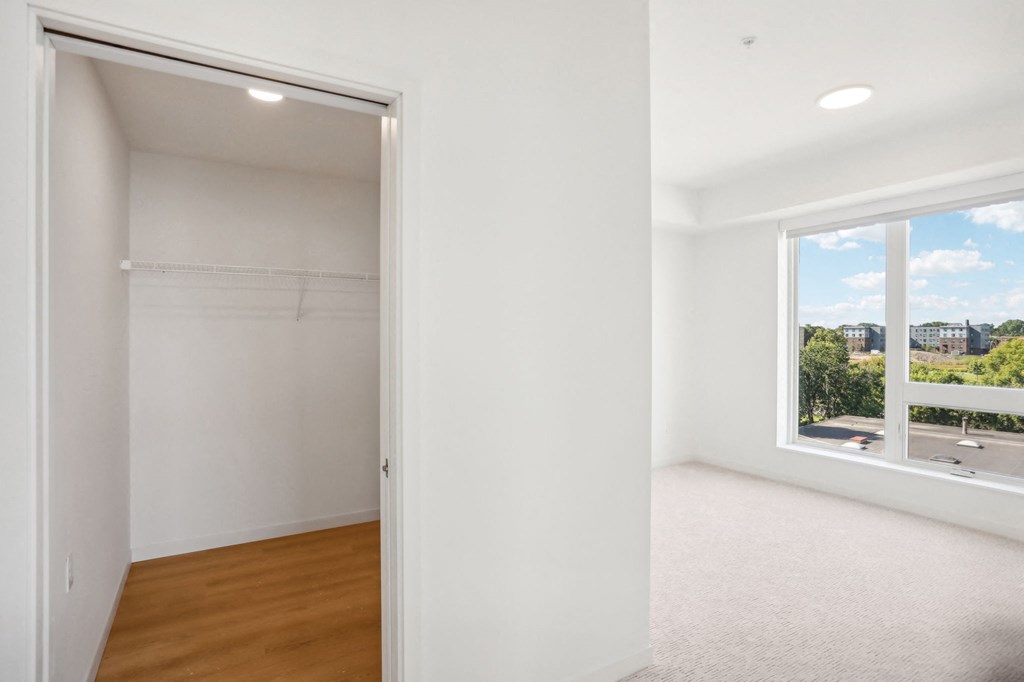 an empty bedroom with a large window and a closet