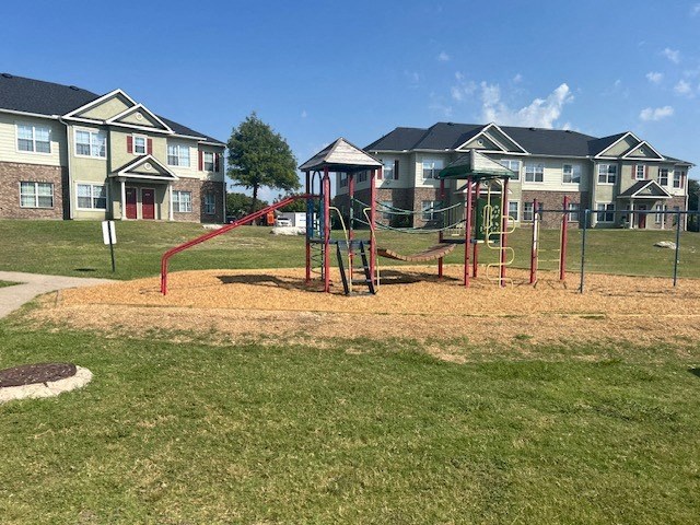 a playground in a park with houses in the background