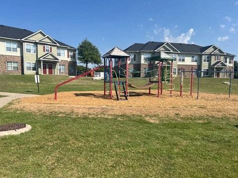 a playground in a park with houses in the background