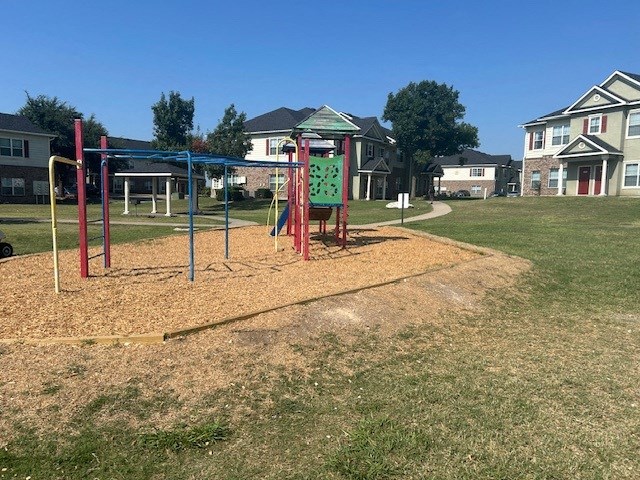 a playground in a park with houses in the background