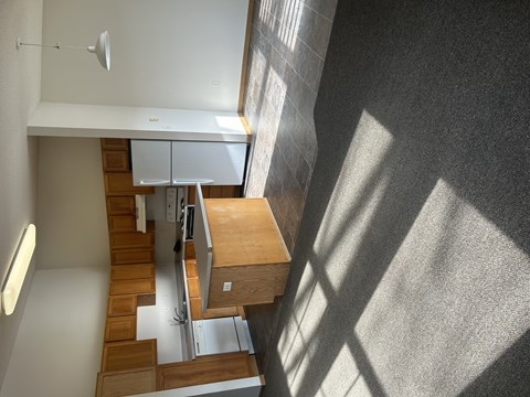 A staircase with a wooden handrail and steps leads up to a kitchen area.