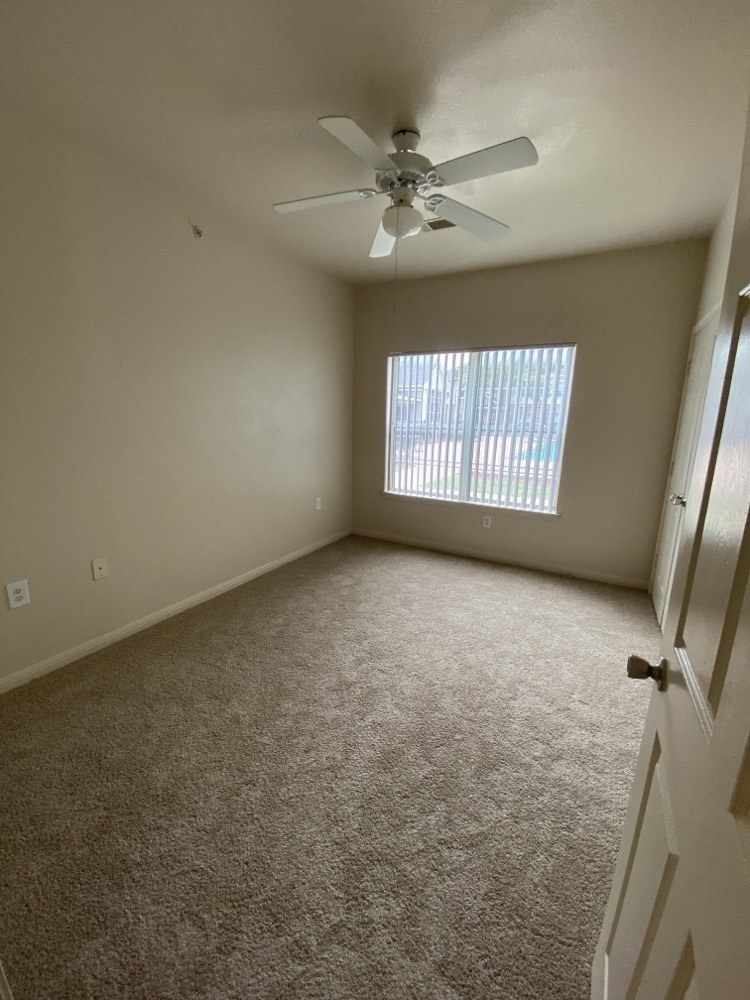 an empty room with a ceiling fan and a window