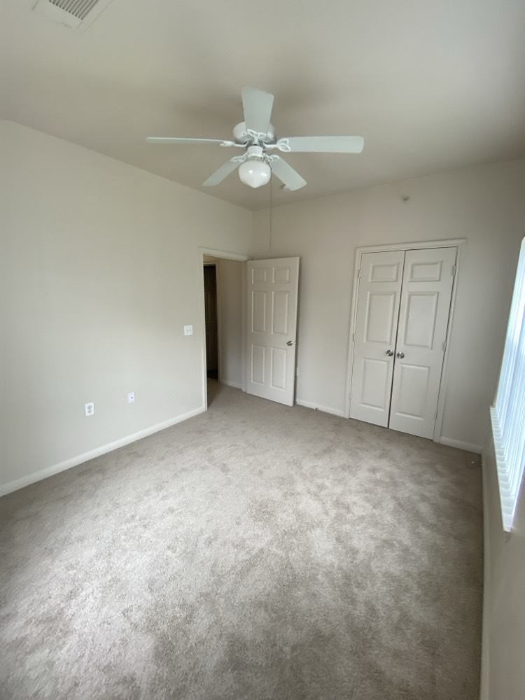 an empty room with a ceiling fan and a door