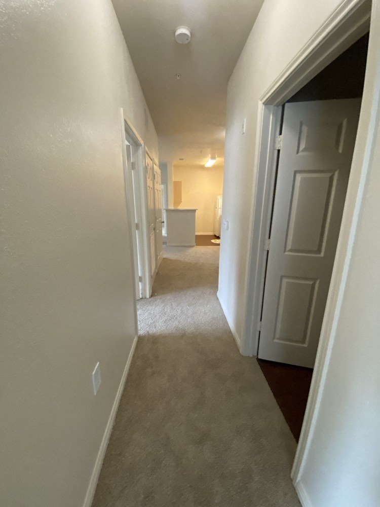 a hallway with a door open to a room and a kitchen