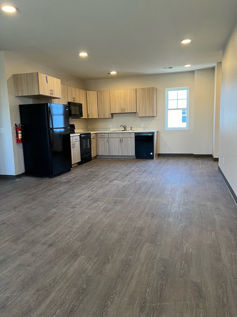 an empty living room and kitchen with wood flooring