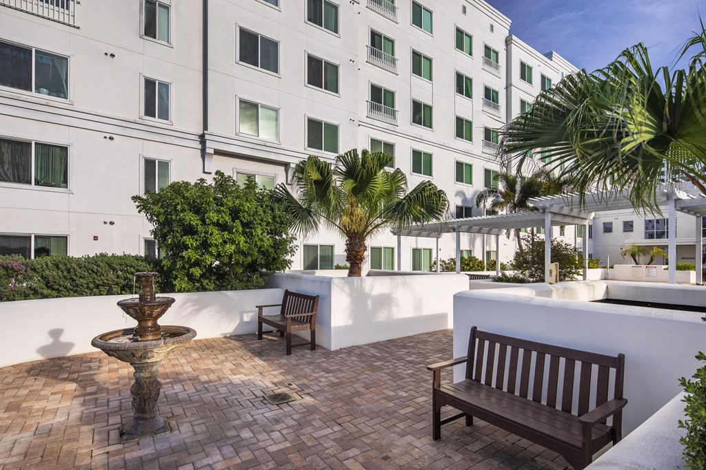 a courtyard with benches and a fountain in front of a building