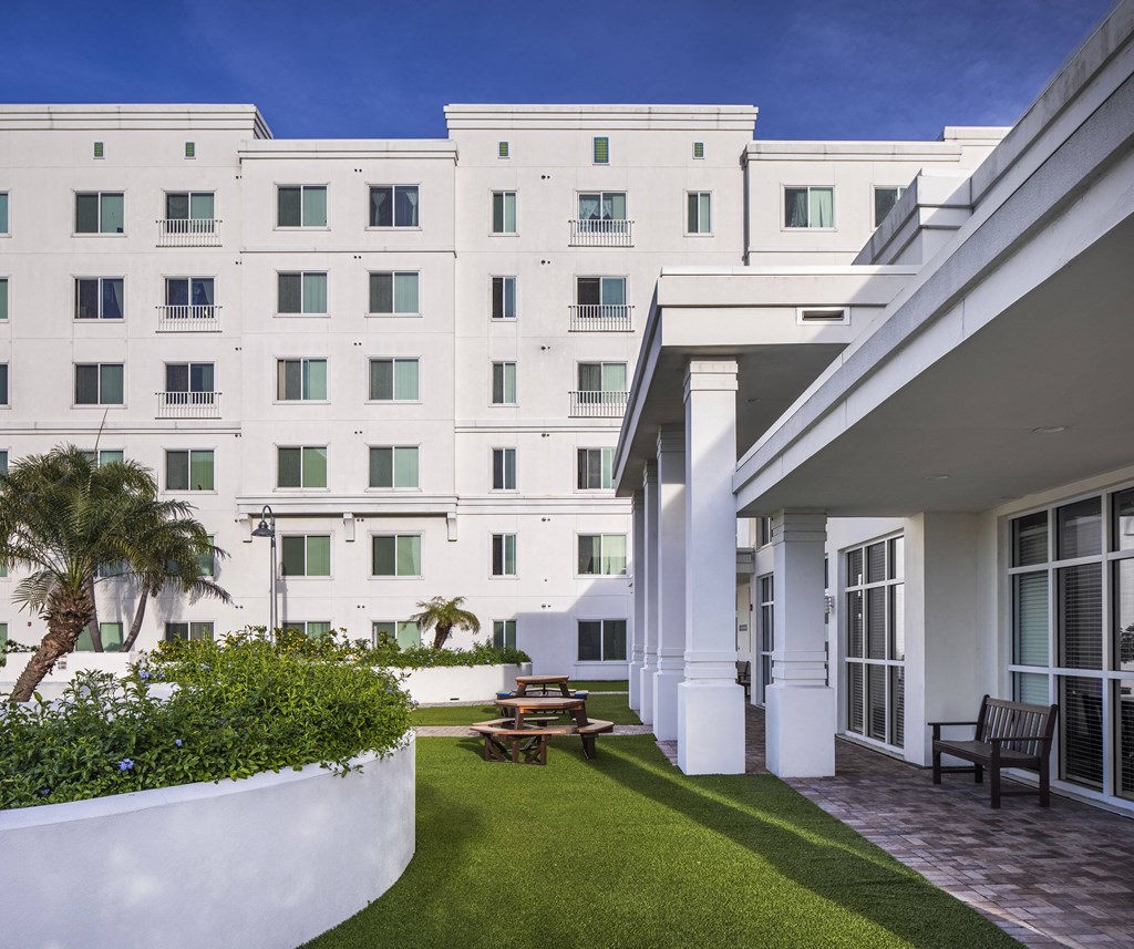 a courtyard with a table and chairs in front of a white building