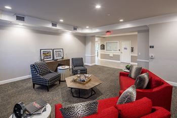 A living room with a red couch and a grey chair.