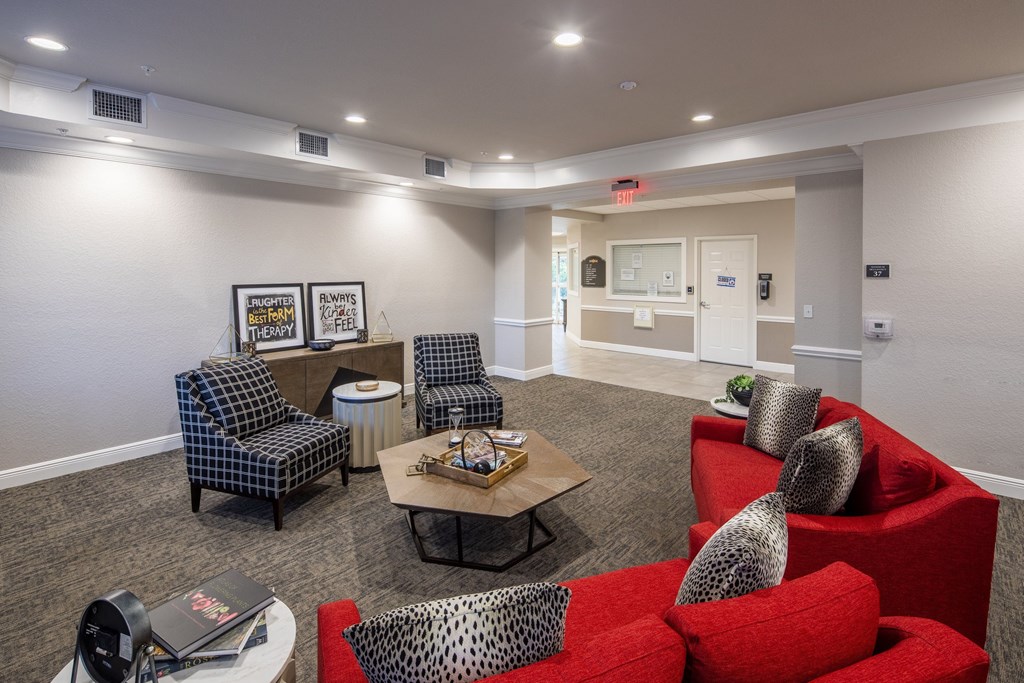 A living room with a red couch and a grey chair.