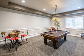 A pool table is in the middle of a room with chairs and a table.